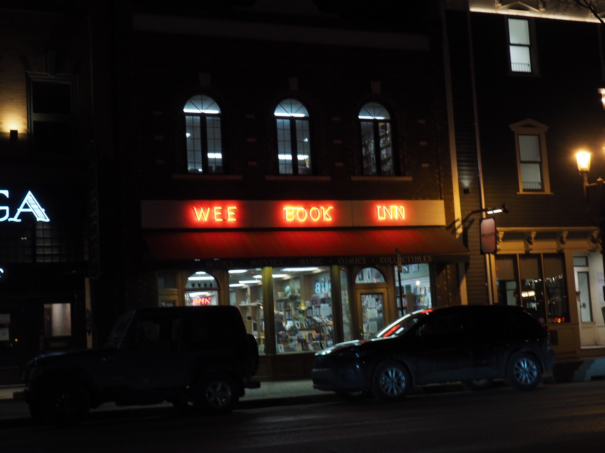 red-lit storefront, parked cars, and brick architecture on a dark edmonton street