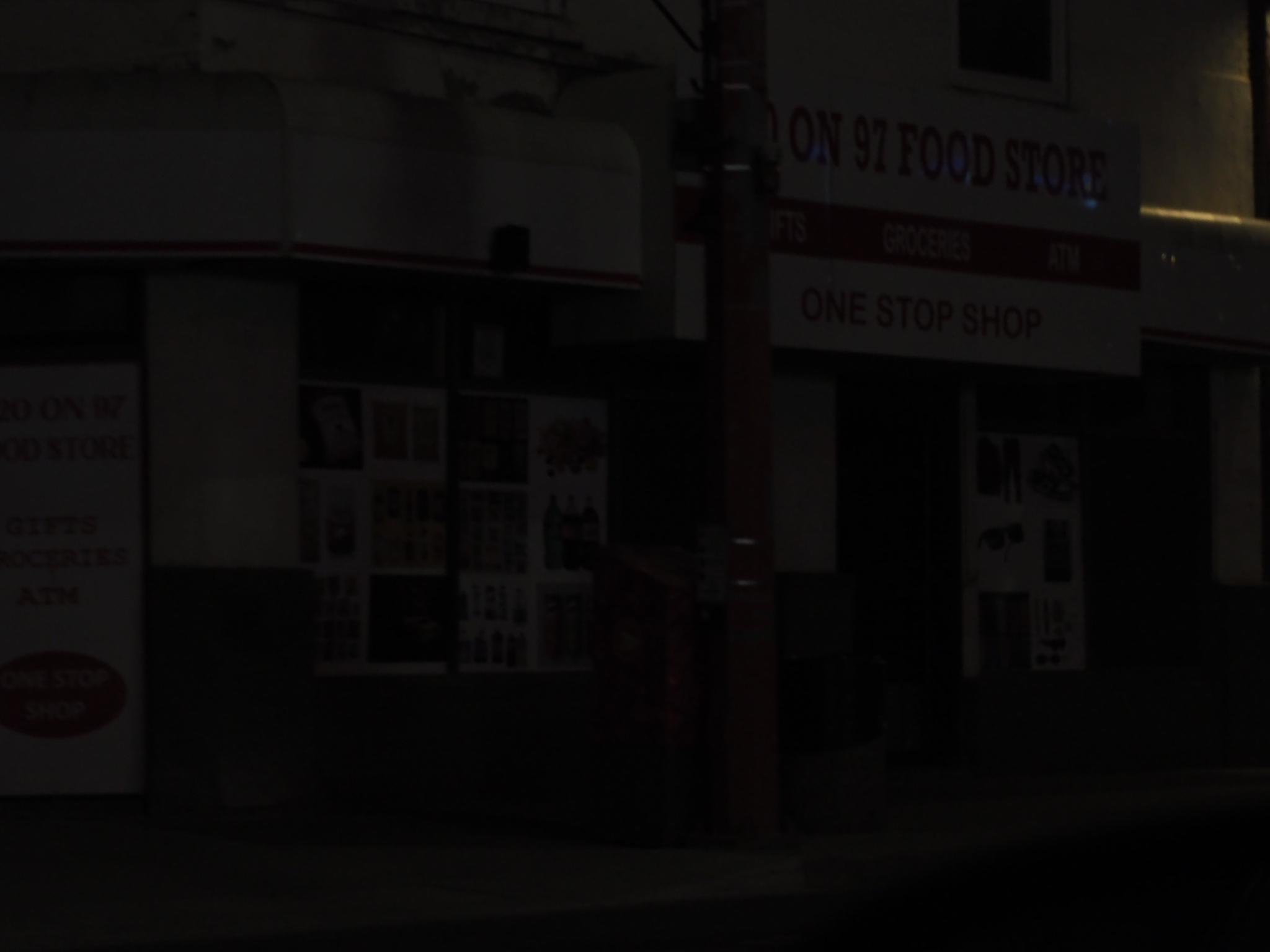 nearly dark storefront with a faint sign and reflections on an edmonton street