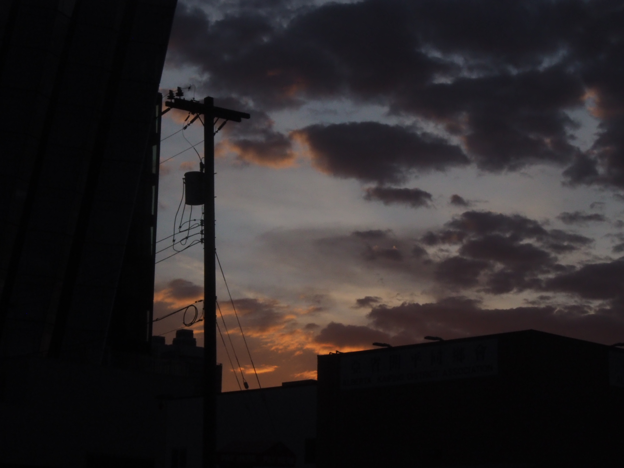rooftops and utility pole silhouetted beneath an orange evening sky in edmonton