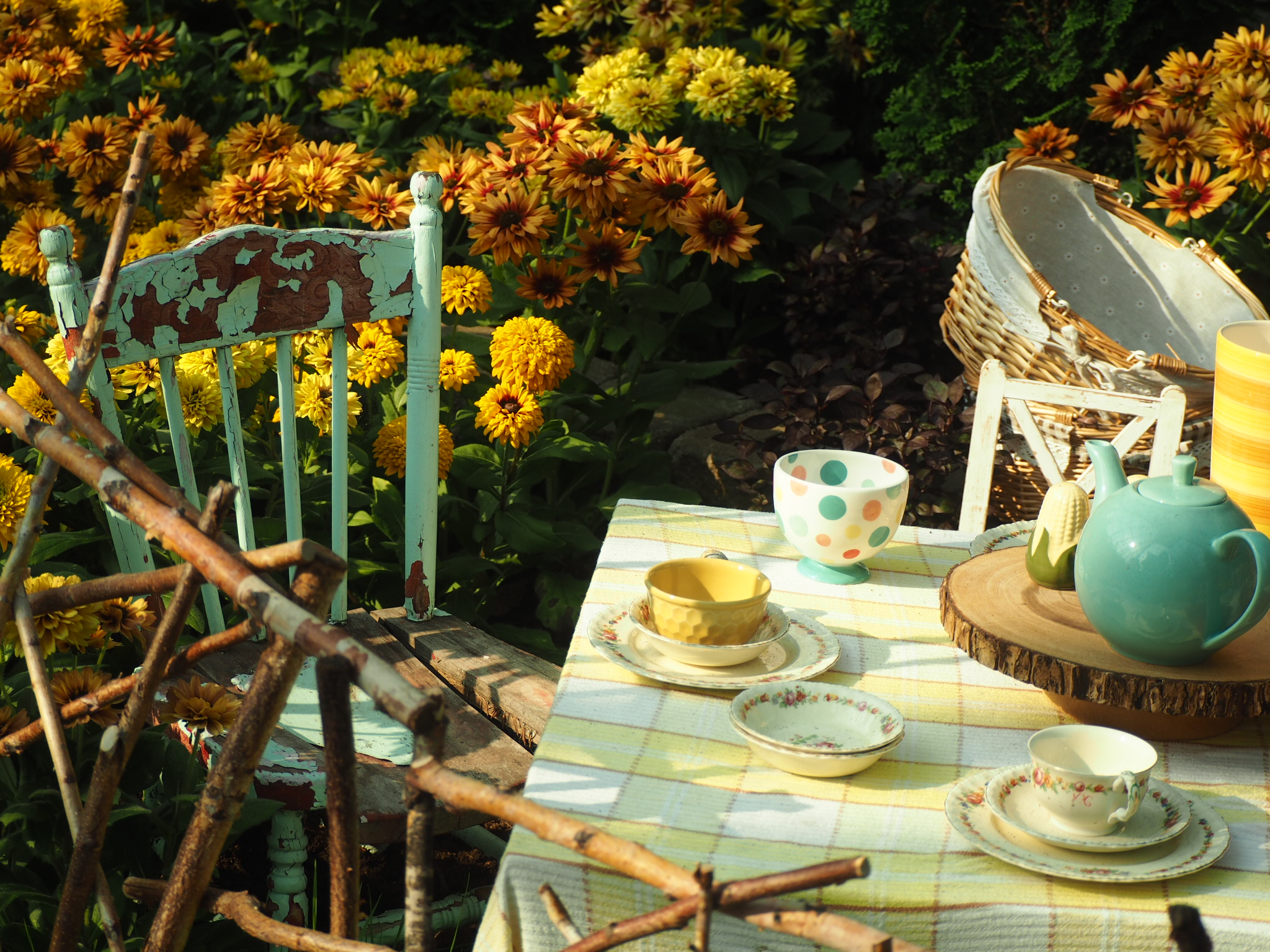 whimsical outdoor tea table with teacups, chairs, yellow flowers, and a watering can near edmonton