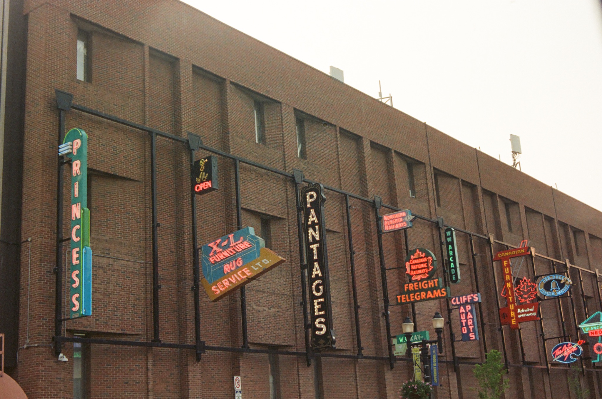 vintage neon signs on a brick building, including 'princess', 'pantages', 'freight telegrams', and 'auto parts'.