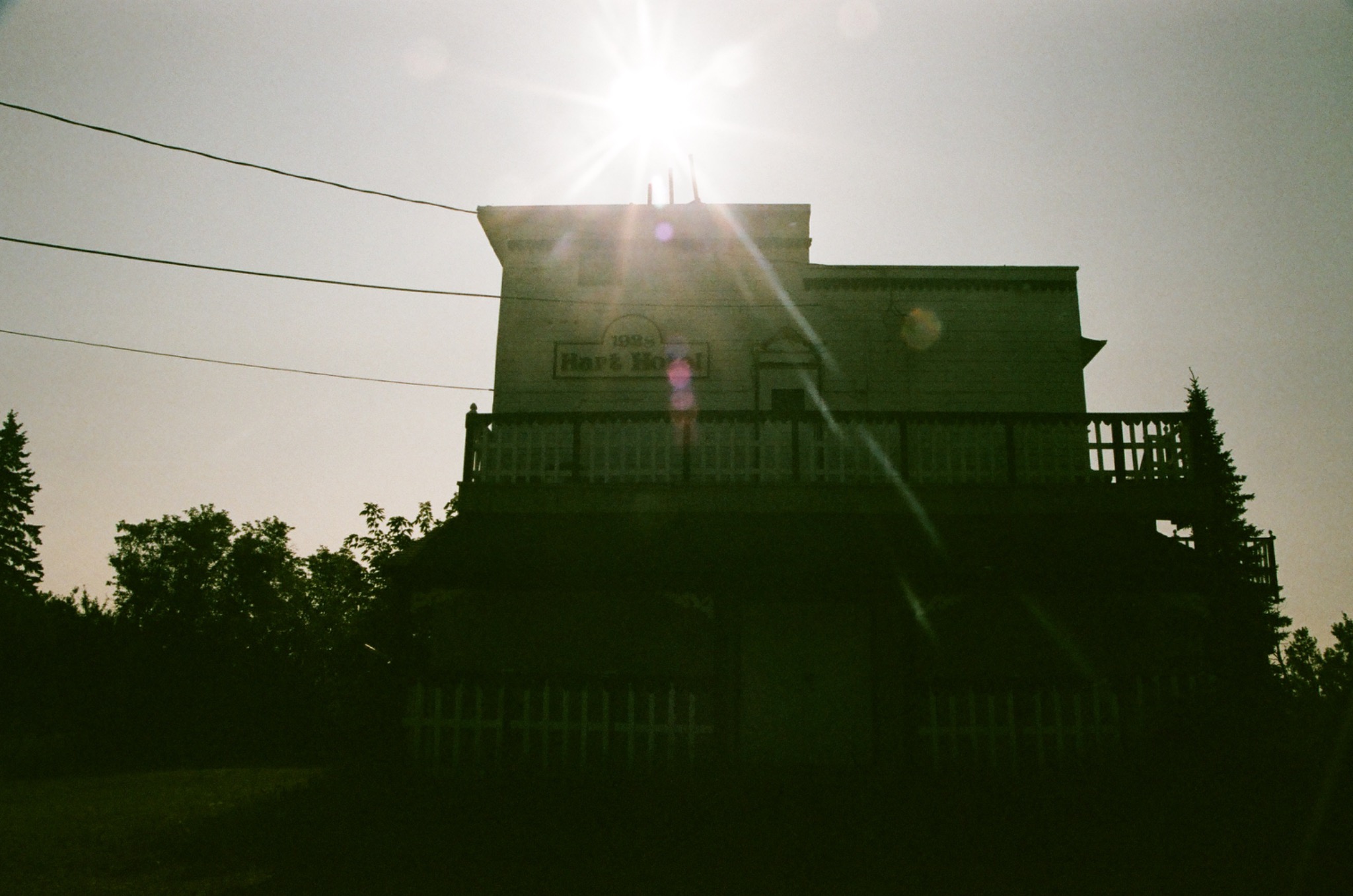 silhouette of hart hotel against bright sun with lens flare, power lines, and trees