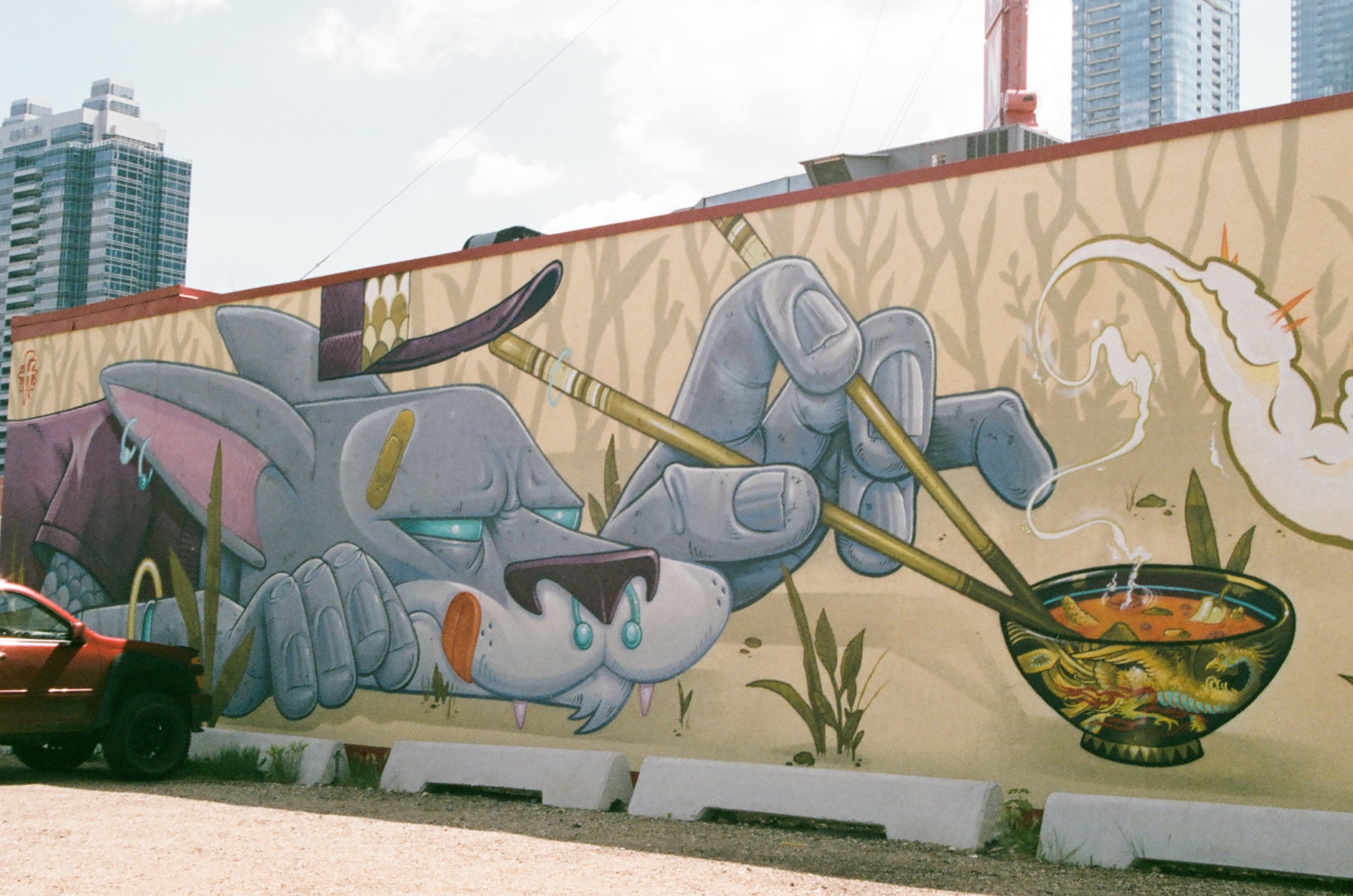mural of a grey wolf-like creature eating ramen with chopsticks on a city wall